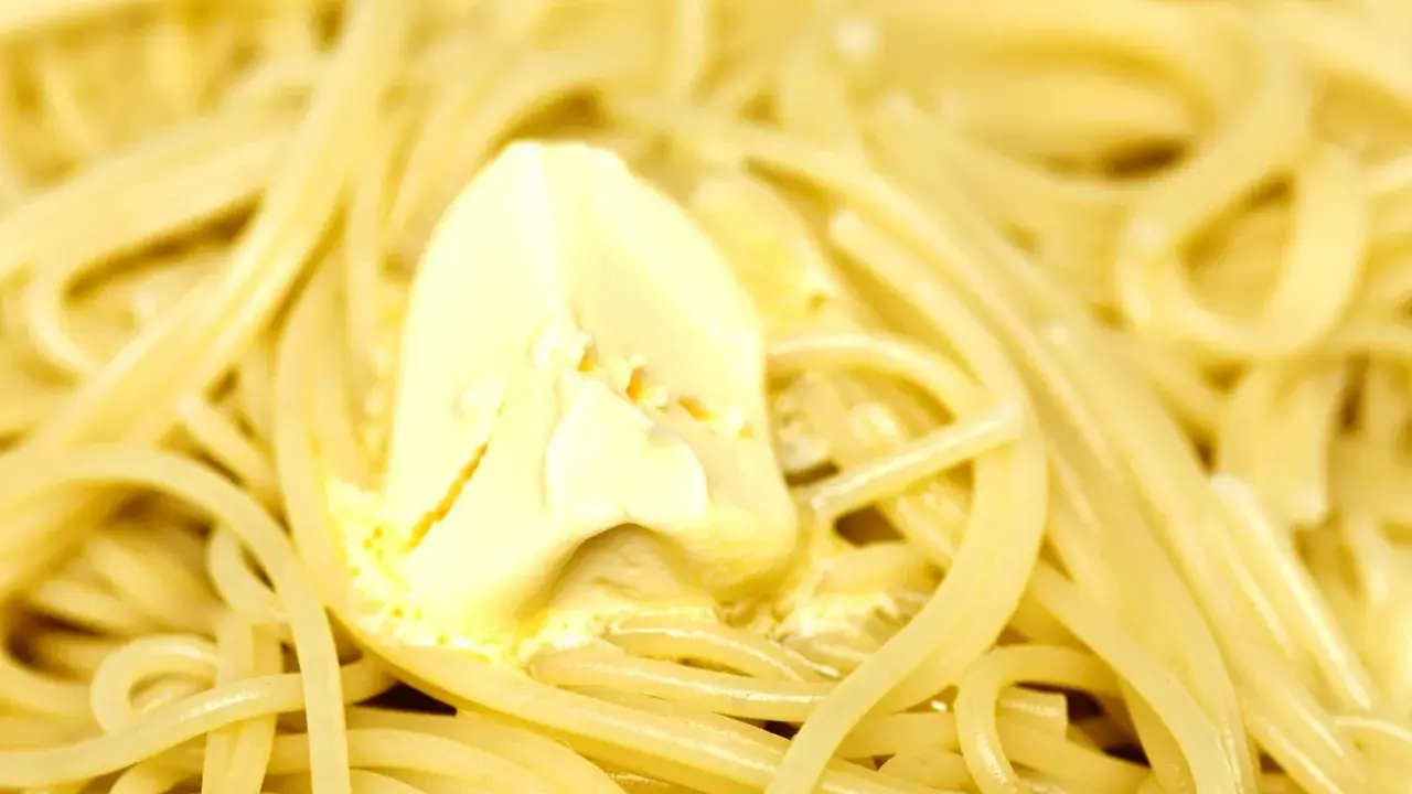 Un piatto di pasta in bianco fumante, con una generosa porzione di burro che si scioglie lentamente.