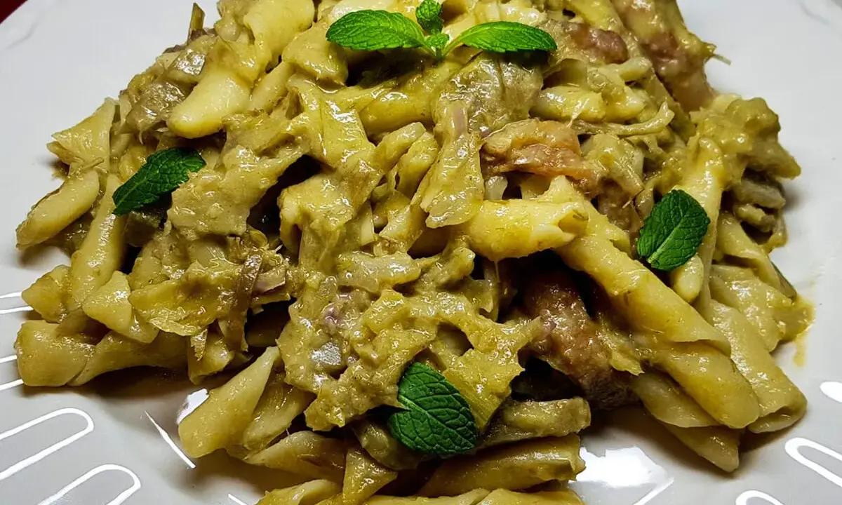 Un piatto invitante di pasta con carciofi, condita con erbe fresche, pronta per essere gustata.