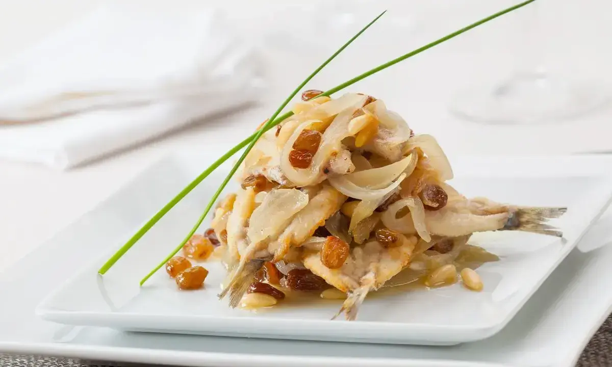 Sarde in saor, un piatto veneziano con sarde, cipolle, uvetta e pinoli, guarnito con erba cipollina.