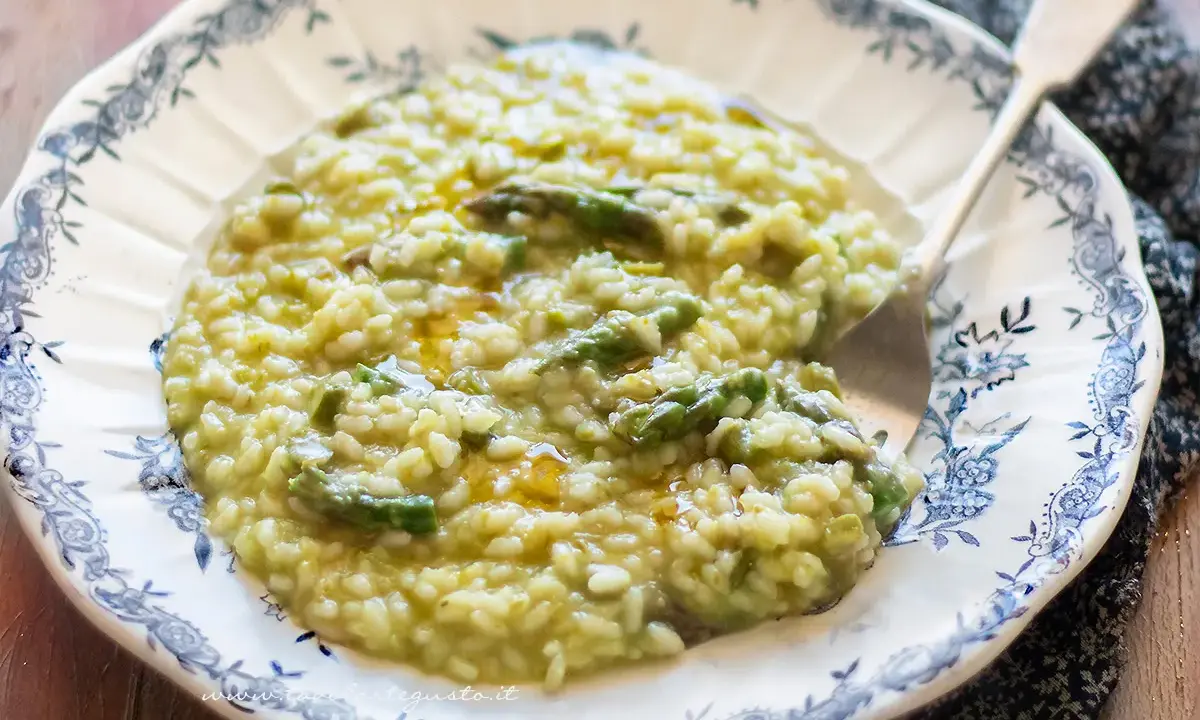 Un cremoso risotto con asparagi, servito in un piatto decorato con un motivo blu. Un piatto primaverile invitante.