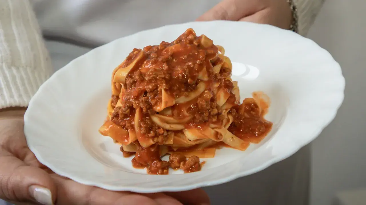 Un piatto di tagliatelle al ragù, un classico della cucina italiana, servito su un piatto bianco.