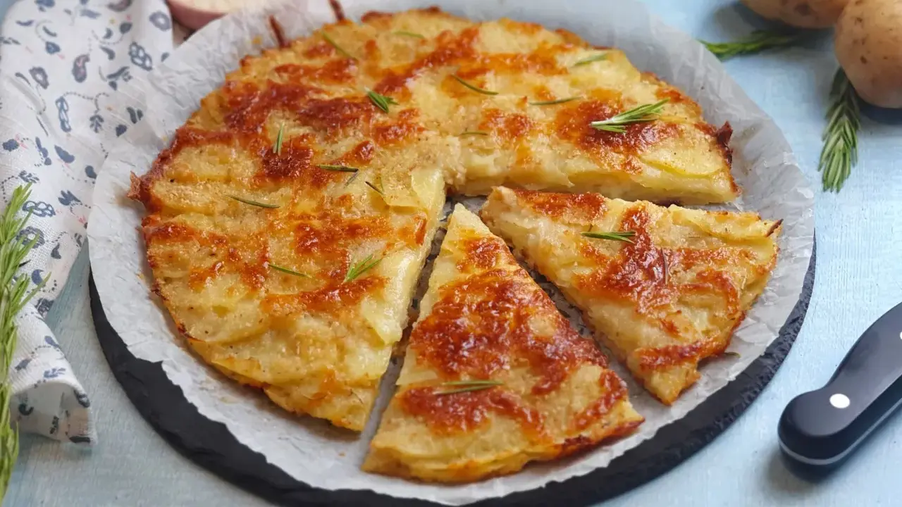 Una deliziosa torta di patate dorata e croccante, guarnita con rosmarino fresco, pronta per essere gustata.