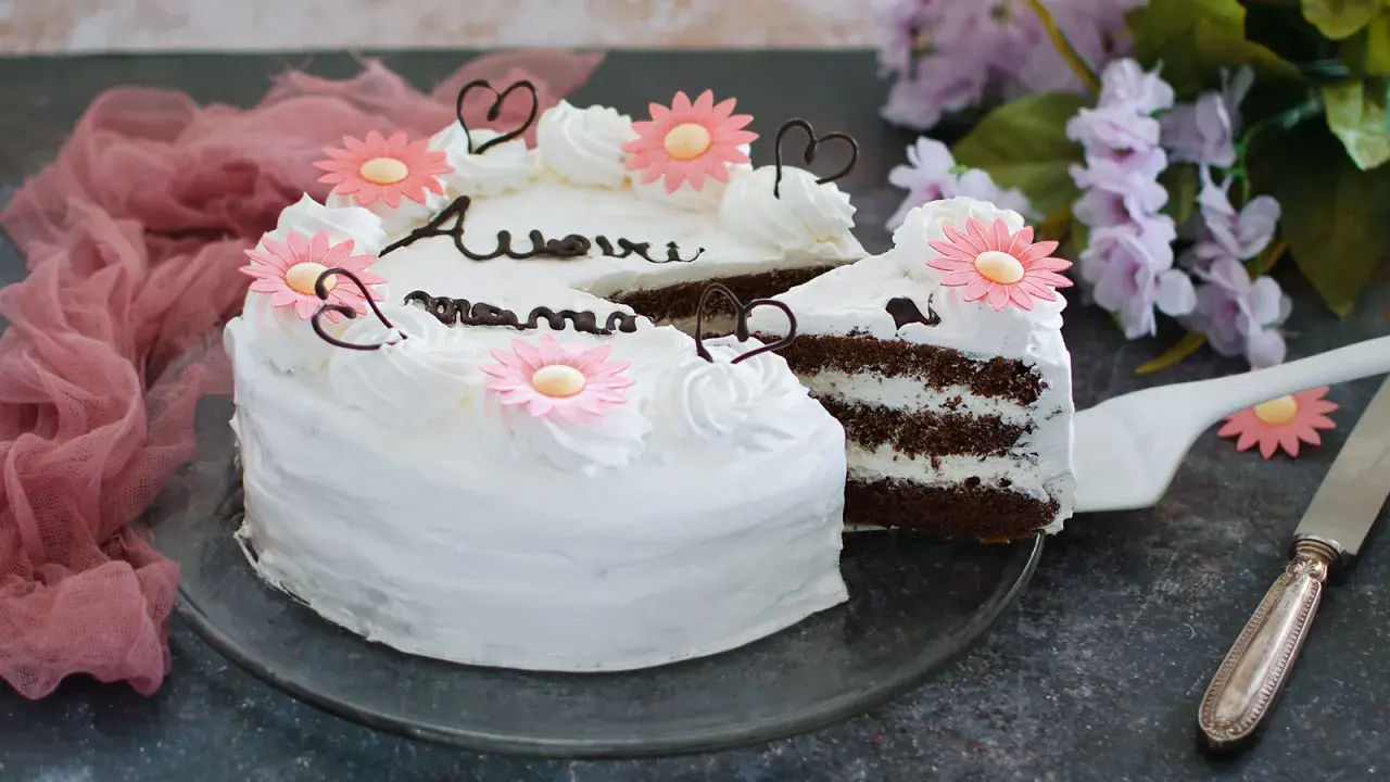 Torta decorata con fiori rosa e scritte in cioccolato, perfetta per la torta festa della mamma. Un dolce per celebrare con amore.