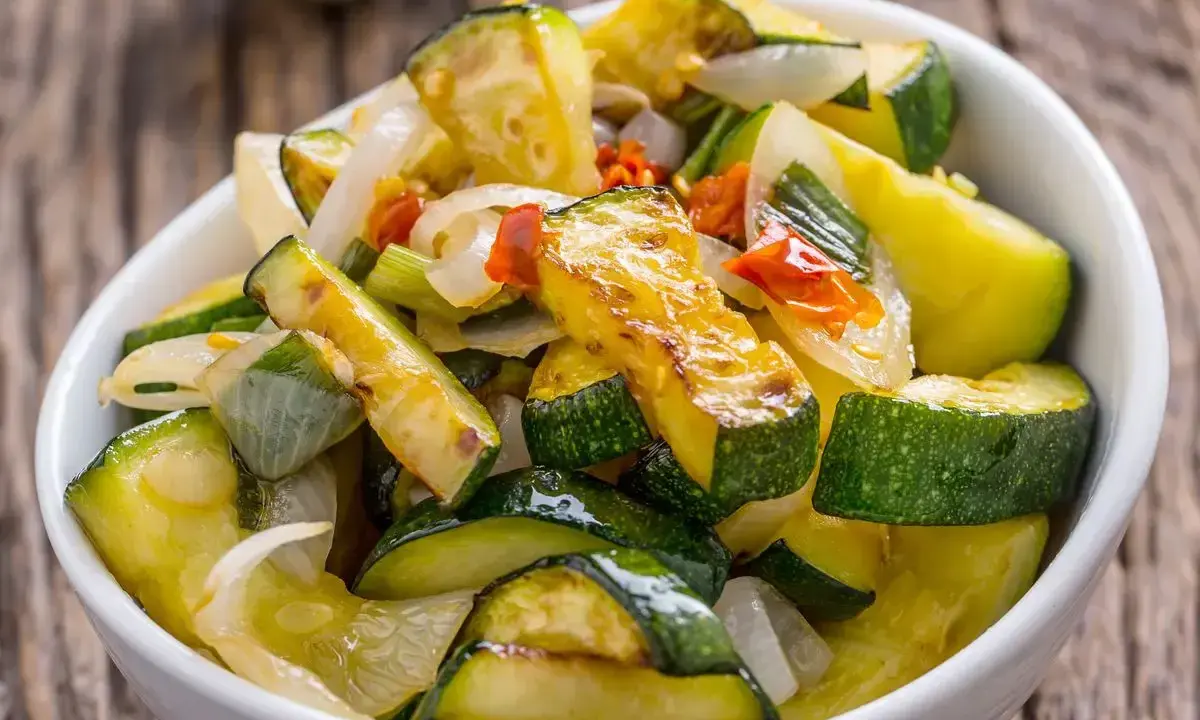 Zucchine in padella, dorate e saporite, con cipolla e peperoncino. Un contorno leggero e gustoso.