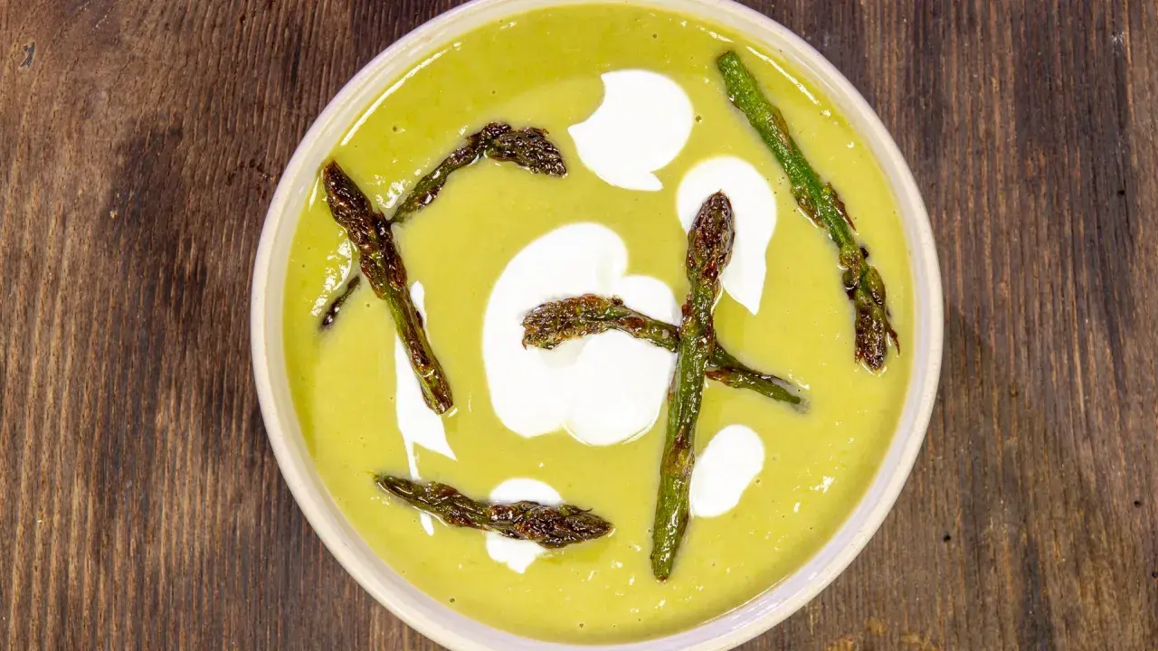Crema di asparagi vellutata, guarnita con asparagi croccanti e un tocco di panna.