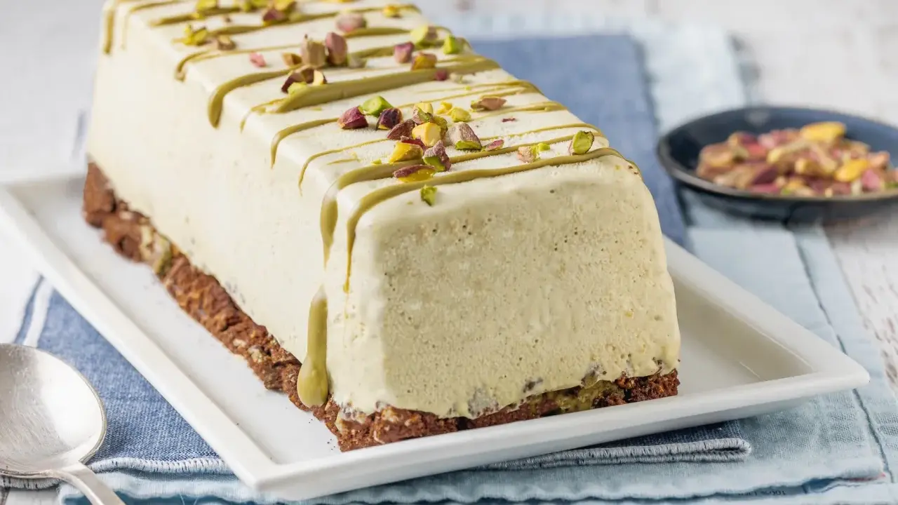Semifreddo al pistacchio decorato con glassa verde e granella di pistacchi, su base croccante.