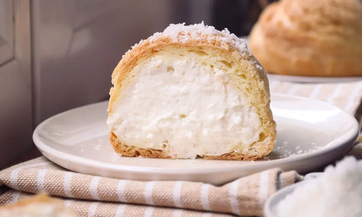 Bignè ripieno di crema soffice, cosparso di zucchero a velo che ricorda un fiocco di neve.
