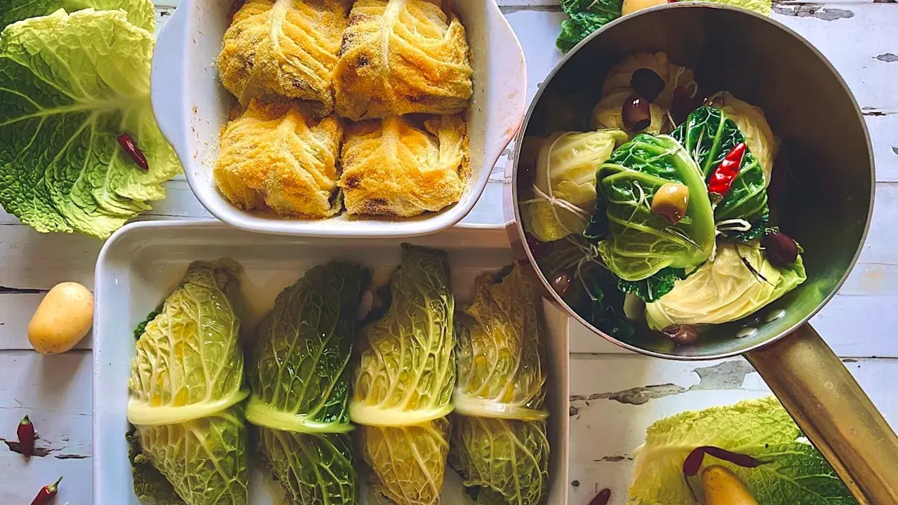 Involtini di verza pronti per essere cotti, alcuni impanati, altri legati con filo, con patate e peperoncini intorno.