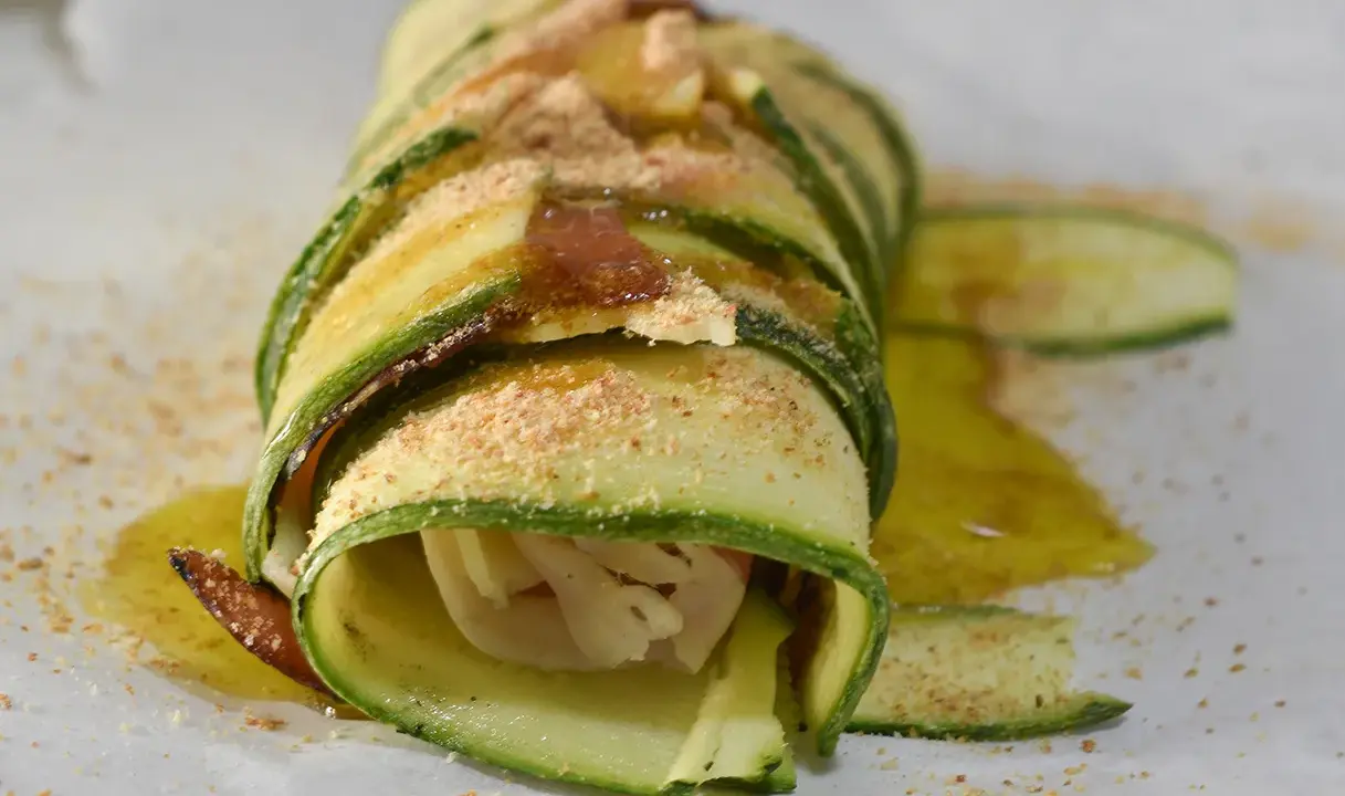 Delizioso rotolo di zucchine, avvolto con cura e cosparso di pangrattato e olio d'oliva. Un piatto leggero e gustoso.