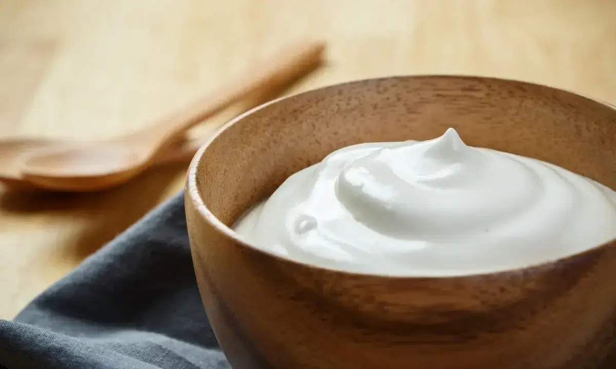 Una ciotola di legno contiene una soffice crema al latte, pronta per essere gustata.