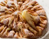 Una deliziosa torta di mele, cosparsa di zucchero a velo, con una fetta appena tolta che rivela la morbidezza dell'interno.