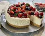 Deliziosa torta fredda allo yogurt, guarnita con fragole, lamponi, mirtilli e una colata di marmellata. Perfetta per un dessert estivo.