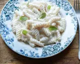 Fusilli cremosi conditi con una salsa vellutata alla ricotta, guarniti con foglie di menta fresca su un piatto decorato.