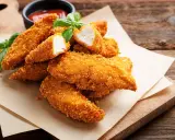 Bocconcini di pollo dorati e croccanti, cotti in friggitrice ad aria, serviti con basilico fresco e salsa.