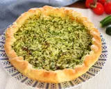 Torta salata con zucchine grattugiate e ricotta, con bordo dorato e decorazione blu su piatto bianco.