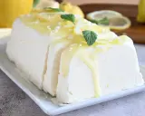 Un delizioso semifreddo al limone, guarnito con scorzette, menta e una glassa gialla, pronto per essere gustato.