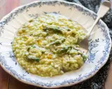 Un cremoso risotto con asparagi, servito in un piatto decorato con un motivo blu. Un piatto primaverile invitante.