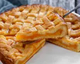 Una fetta di crostata senza glutine con ripieno di albicocche dorate, la sua pasta friabile e la griglia decorativa invitano a un assaggio goloso.