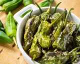 Friggitelli in padella, cotti e lucidi, cosparsi di sale grosso, in una ciotola bianca.