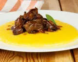 Piatto di polenta e osei, con uccellini scuri in umido e una foglia di salvia.