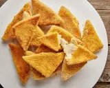 Mozzarella in carrozza al forno, triangolini dorati e croccanti con cuore filante di formaggio fuso, serviti su un piatto bianco.