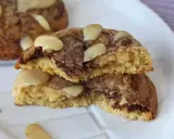 Biscotti alla cannella con gocce di cioccolato e mandorle, uno spezzato mostra l'interno morbido e profumato.