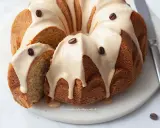 Deliziosa torta al caffè con glassa chiara e chicchi di caffè come decorazione. Una fetta è stata tagliata, mostrando la morbida consistenza interna.