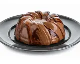 Deliziosa bavarese al cioccolato con glassatura lucida e striature di cioccolato fondente su piatto scuro.