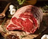 Un succulento pezzo di carne cruda, pronto per diventare un delizioso brasato di manzo. Spezie, erbe aromatiche e aglio completano la scena.