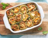 Involtini di zucchine al forno, ripieni di prosciutto e formaggio, dorati e croccanti, guarniti con basilico fresco.