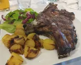 Costata di manzo succulenta con patate arrosto e insalata fresca, un piatto da re.