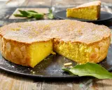 Una deliziosa caprese al limone, cosparsa di zucchero a velo e scorzetta d'arancia, con mandorle sui bordi.