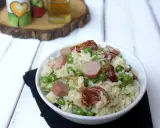 Una ciotola di insalata di riso con piselli, salsiccia e pomodori secchi, pronta per essere gustata.