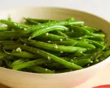 Fagiolini in padella conditi con aglio e pepe, serviti in una ciotola di legno.