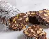 Salame di cioccolato senza uova ricetta della nonna, con biscotti, nocciole e pistacchi, spolverato di zucchero a velo.