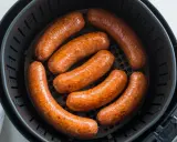 Salsiccia dorata e succulenta in friggitrice ad aria, pronta per essere gustata.