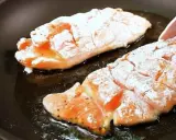 Due filetti di petto di pollo infarinati cuociono in padella, sfrigolando nell'olio caldo.