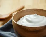Una ciotola di legno contiene una soffice crema al latte, pronta per essere gustata.