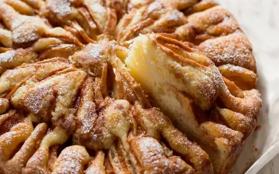 Una deliziosa torta di mele, cosparsa di zucchero a velo, con una fetta appena tolta che rivela la morbidezza dell'interno.