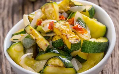 Zucchine in padella, dorate e saporite, con cipolla e peperoncino. Un contorno leggero e gustoso.