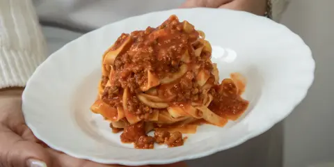 Un piatto di tagliatelle al ragù, un classico della cucina italiana, servito su un piatto bianco.