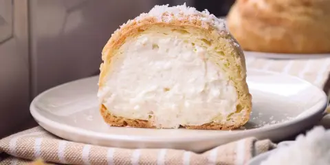 Bignè ripieno di crema soffice, cosparso di zucchero a velo che ricorda un fiocco di neve.