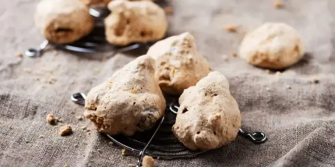 Biscotti meringati, dall'aspetto rustico ma dal sapore delizioso, noti come "brutti ma buoni", su una griglia.