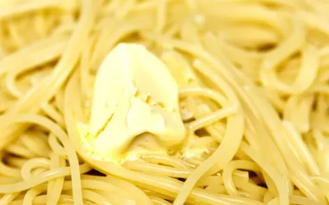 Un piatto di pasta in bianco fumante, con una generosa porzione di burro che si scioglie lentamente.