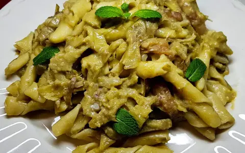 Un piatto invitante di pasta con carciofi, condita con erbe fresche, pronta per essere gustata.