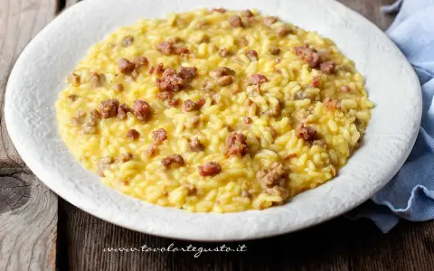 Un cremoso risotto con salsiccia, servito su un piatto bianco, pronto per essere gustato.
