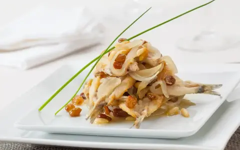 Sarde in saor, un piatto veneziano con sarde, cipolle, uvetta e pinoli, guarnito con erba cipollina.