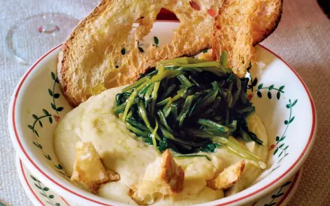 Piatto di fave e cicoria con crostini di pane abbrustolito.