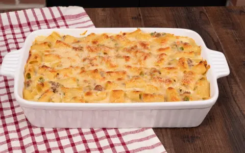 Un invitante pasta al forno bianca, con maccheroni dorati, piselli e carne macinata, gratinata al punto giusto.