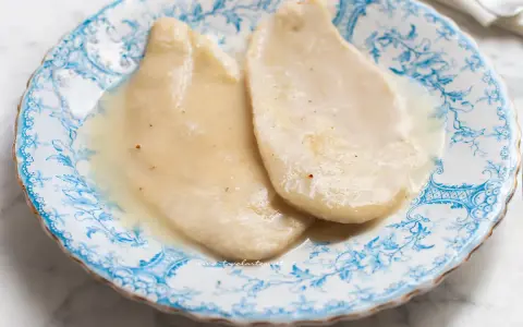 Due scaloppine al vino bianco, tenere e succulente, servite su un piatto decorato con motivi blu.